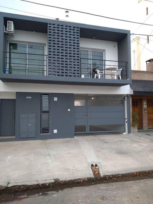 a house with a dog sitting on a balcony at Complejo TuLuz - Dpto 1 dormitorio con cochera y Monoambiente, con cochera opcional en Tolosa, La Plata, in Tolosa