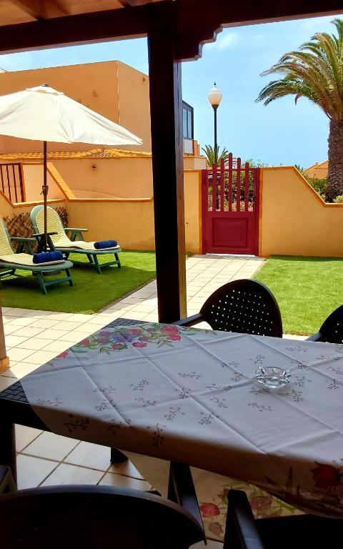 a table with chairs and an umbrella in a yard at GRANI MAR in Costa Calma