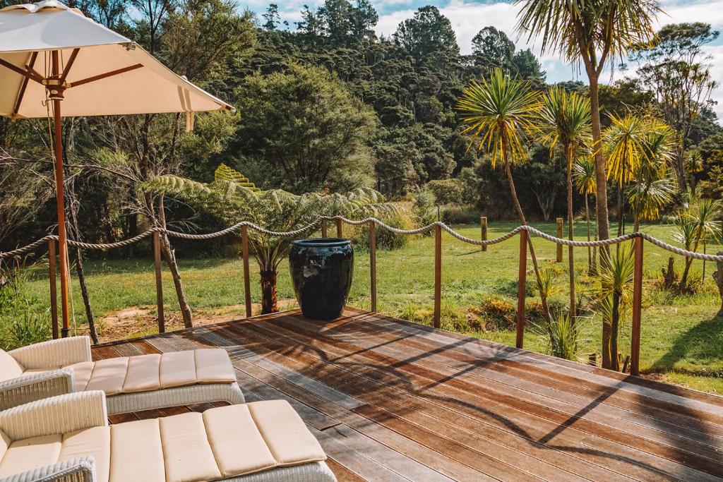 a wooden deck with chairs and an umbrella at Parohe Island Retreat in Auckland