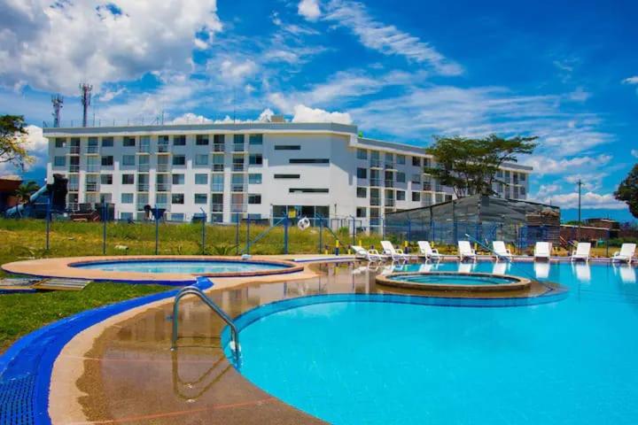 a hotel with three pools with chairs and a building at Apartamento a 2km del Parque del Café in Montenegro