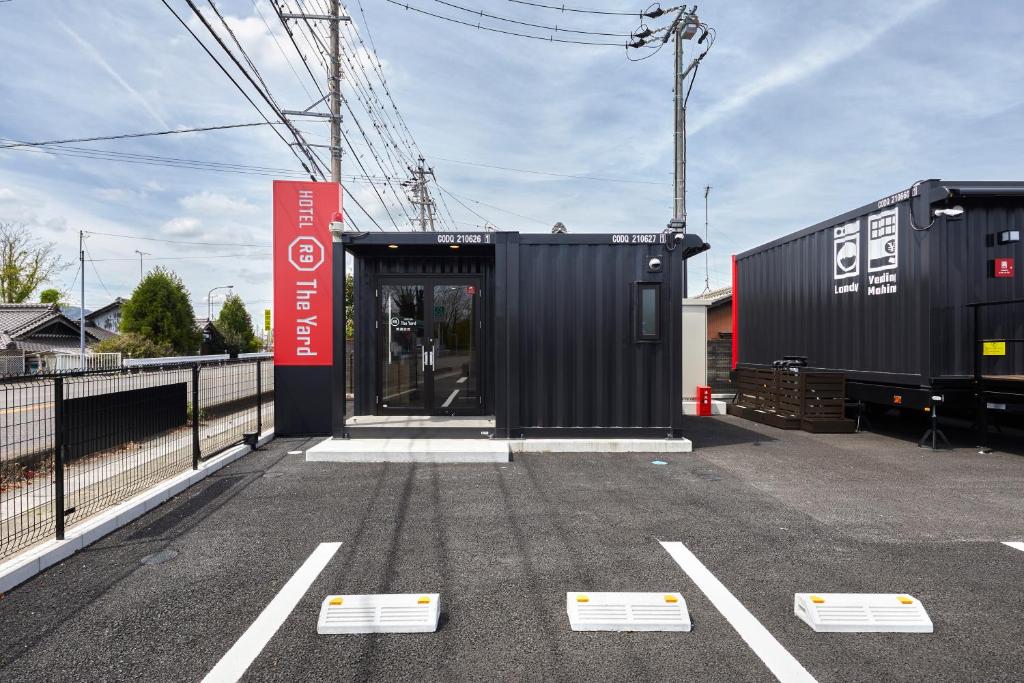 un conteneur de transport noir avec une porte dans un parking dans l'établissement HOTEL R9 The Yard Minokamo, à Minokamo