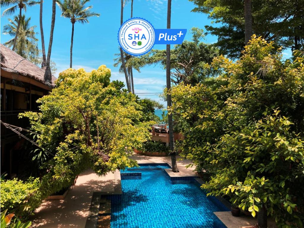 una piscina frente a un complejo con un cartel en Vacation Village Phra Nang Inn - SHA Extra Plus, en Ao Nang Beach