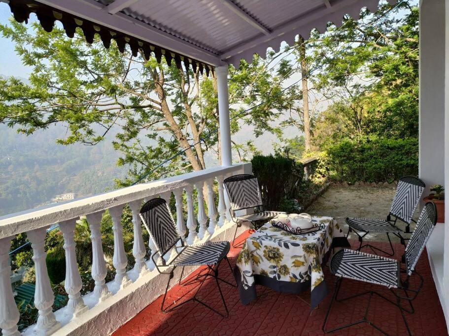 einen Tisch und Stühle auf einem Balkon mit Aussicht in der Unterkunft Whistling Thrush Cottage, Bhimtal (2bhk) in Nainital