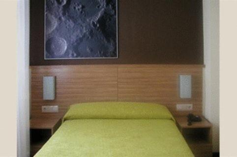 a bedroom with a green bed with a painting on the wall at Hotel Moon in A Coruña