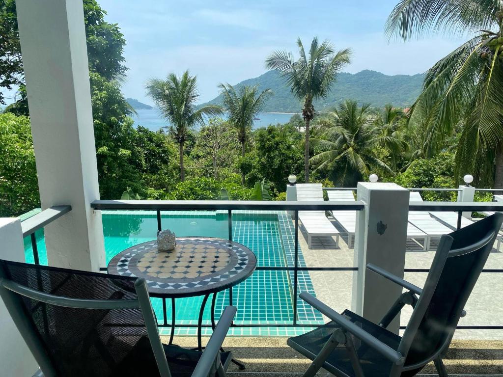 a balcony with a table and chairs and a swimming pool at Villa Seaview Garden in Ko Tao
