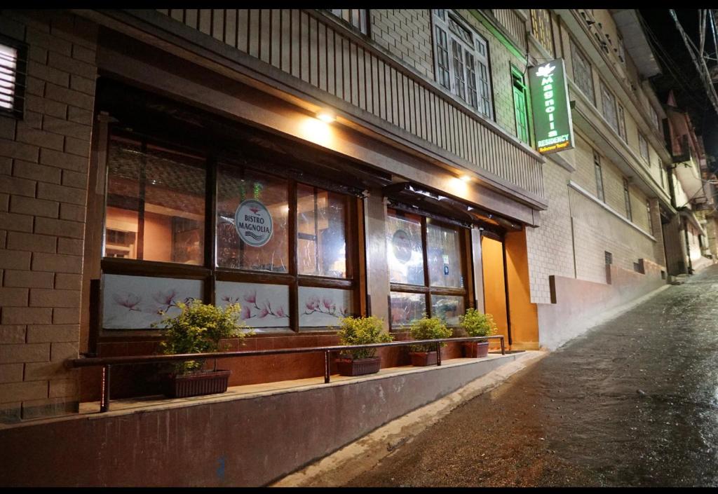 a store front with potted plants in windows on a street at Magnolia Residency in Darjeeling