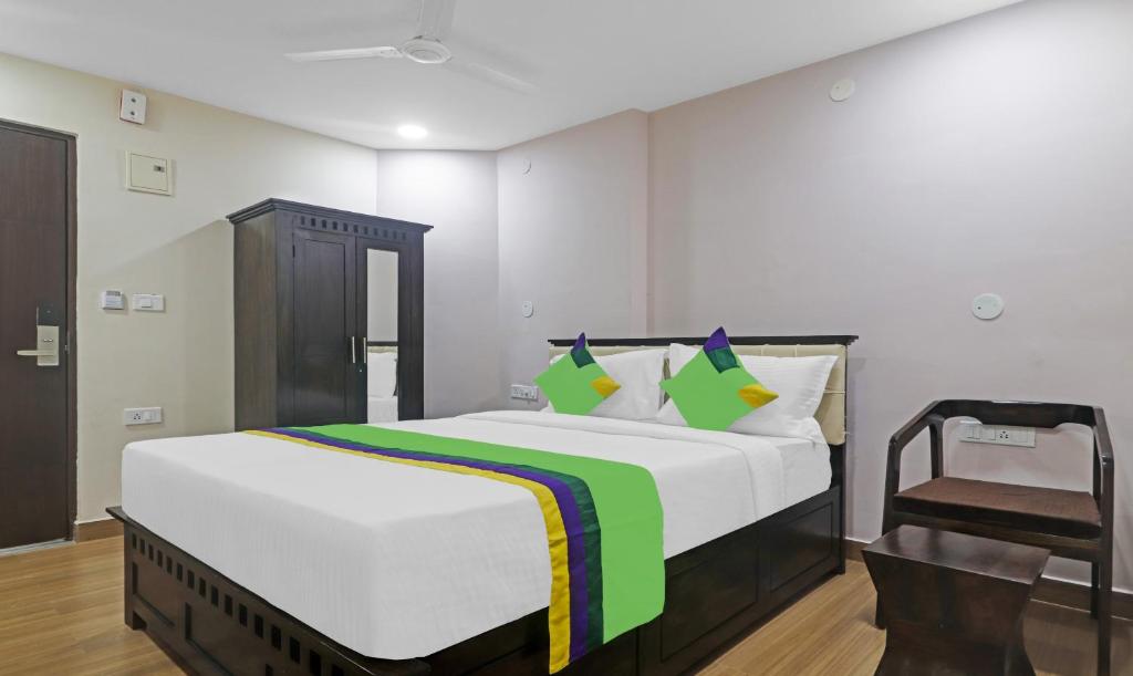 a bedroom with a large bed and a chair at Treebo Trend Purple Square in Hyderabad
