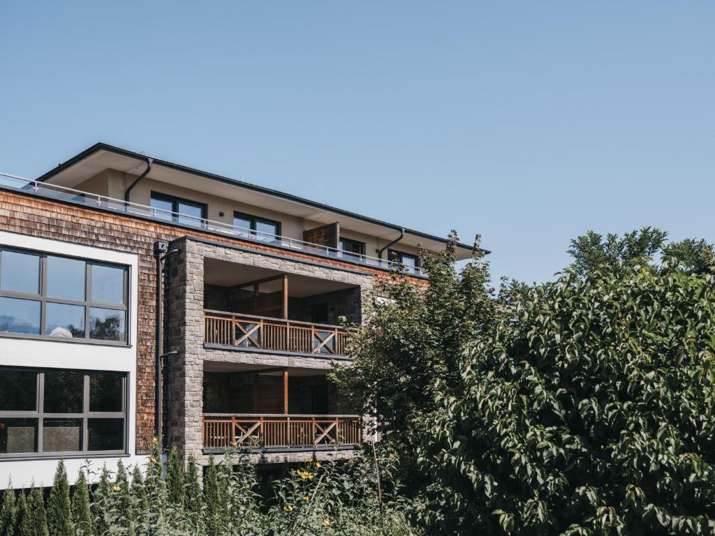 an apartment building with balconies and a tree at Village Park Suites by VAYA inklusive Zell am See Kaprun Sommer Karte in Zell am See