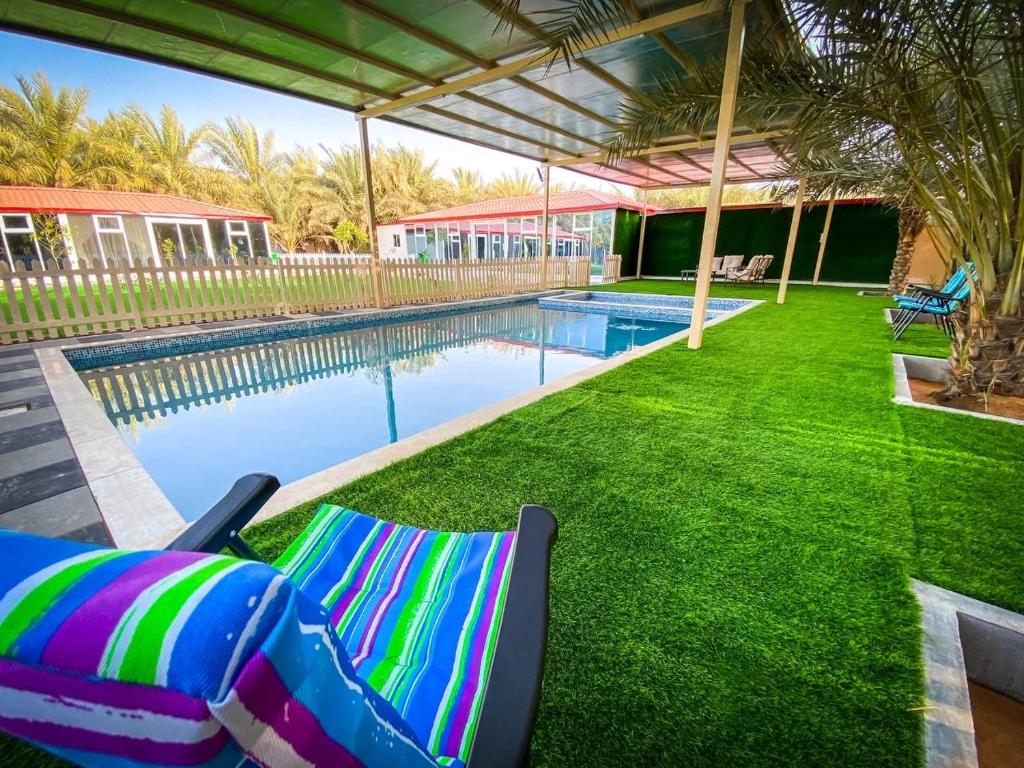a swimming pool with two lounge chairs next to a yard at Palm Escape Farmhouse - By Seven Elements in Ras al Khaimah