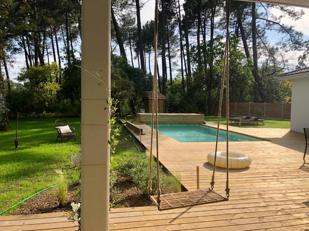 a porch with a swing and a swimming pool at Villa Sophie in Lanton