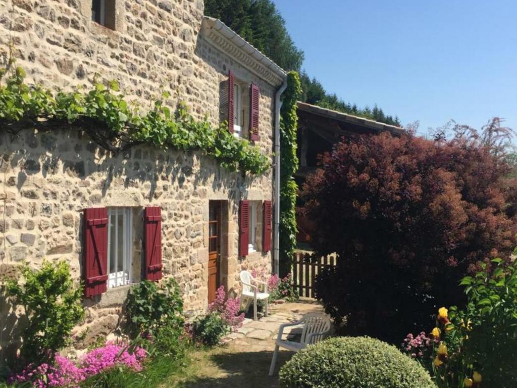 a stone building with red shuttered windows and flowers at Gîte Véranne, 2 pièces, 4 personnes - FR-1-496-255 in Véranne