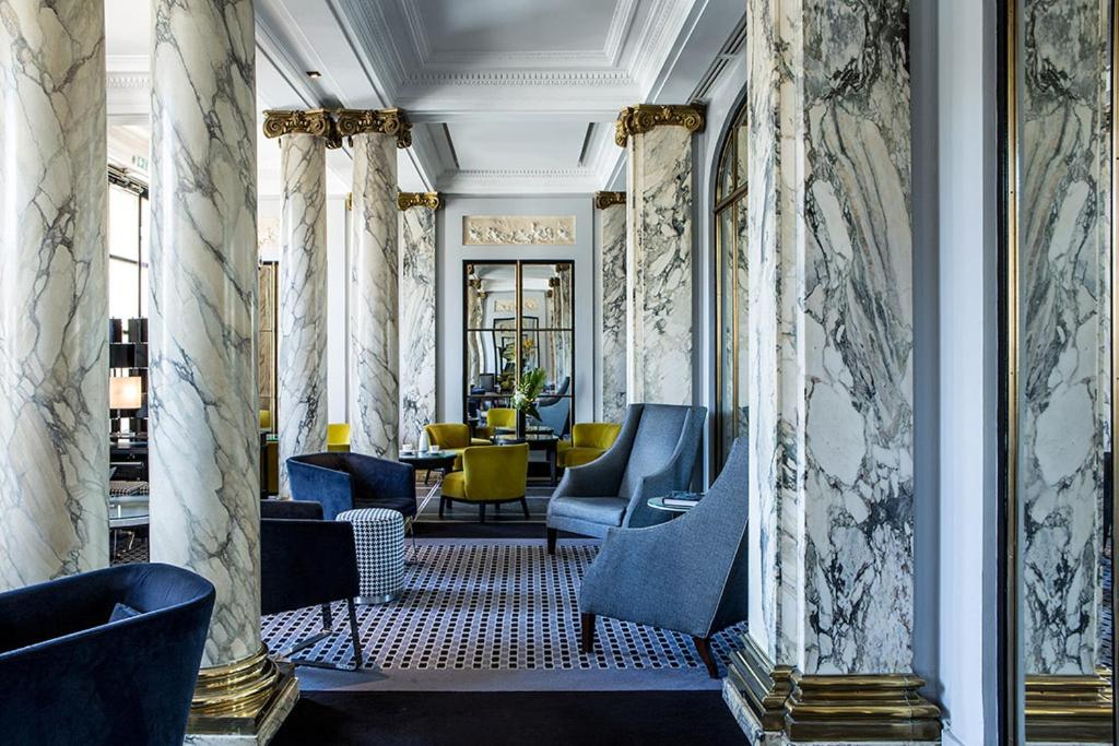 a lobby with blue chairs and a table at Hôtel Brighton - Esprit de France in Paris