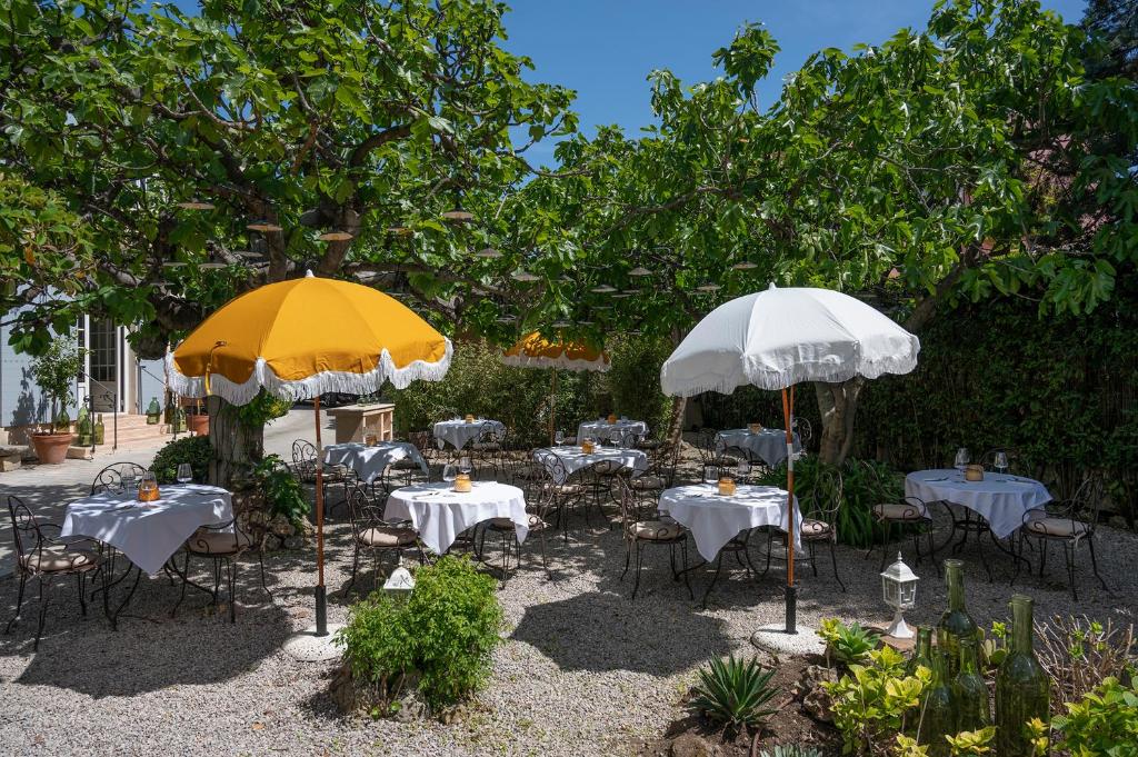 two tables and chairs with umbrellas in a garden at Lou Cagnard in Saint-Tropez