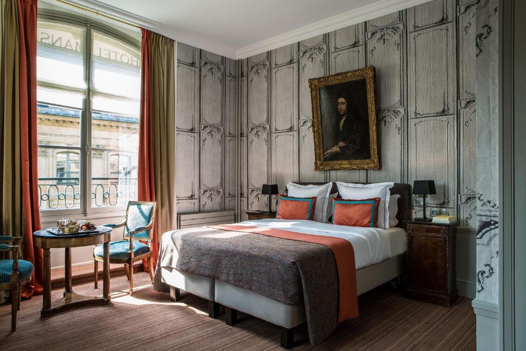 فندق مانسارت - إسبريه دو فرونس في باريس: غرفة نوم بسرير مع لوحة على الحائط
