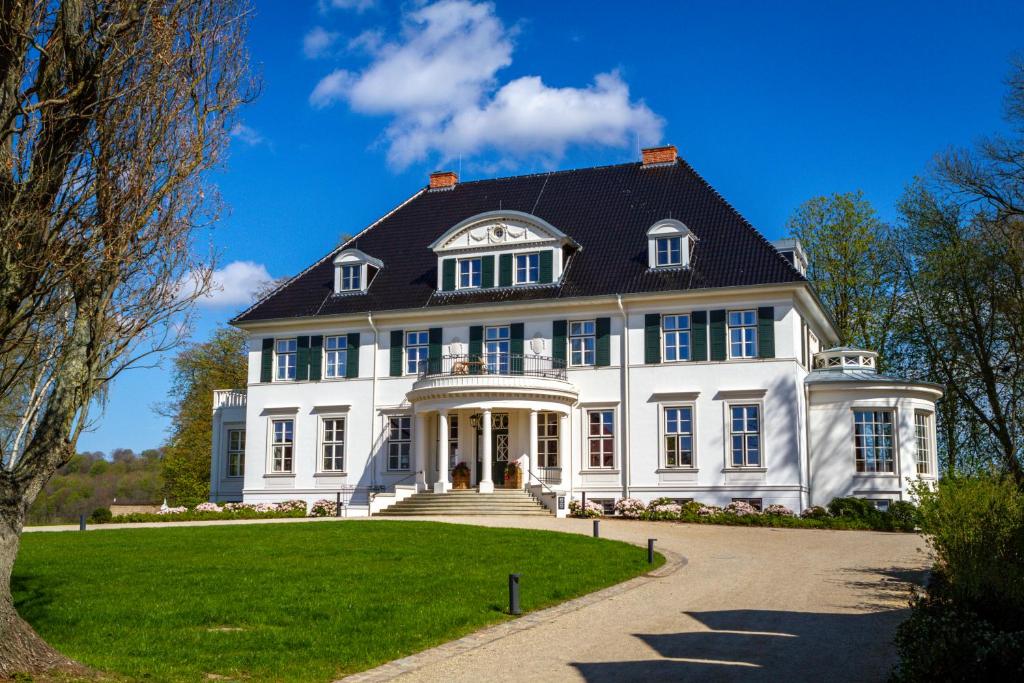 una gran casa blanca con techo negro en Hotel Gut Immenhof en Malente