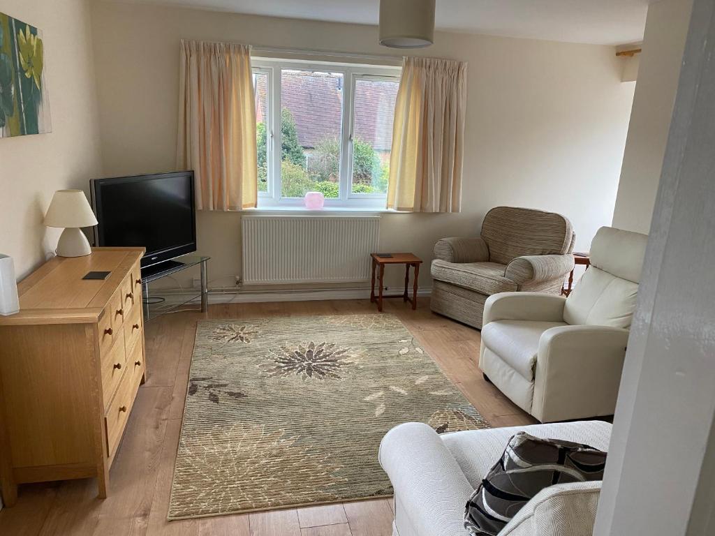 a living room with a tv and a couch and a chair at Spacious first floor apartment in the centre of Church Stretton with free parking in Church Stretton