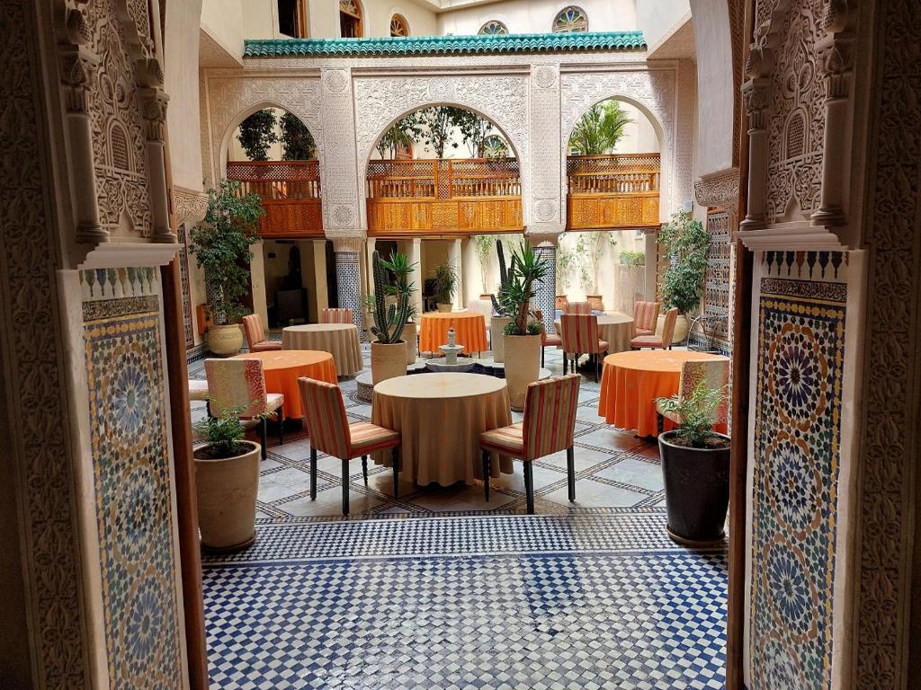 a restaurant with tables and chairs in a building at Riad Andalib in Fès