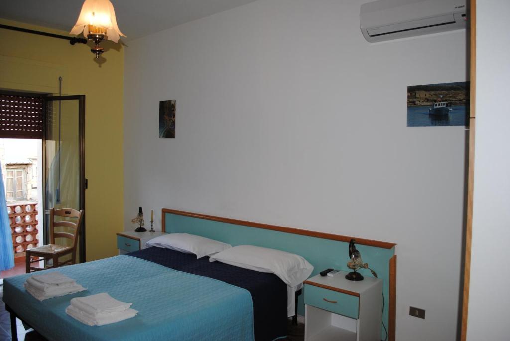 B&b La Scogliera في لا كاستيلا: غرفة نوم بسرير ولحاف ازرق