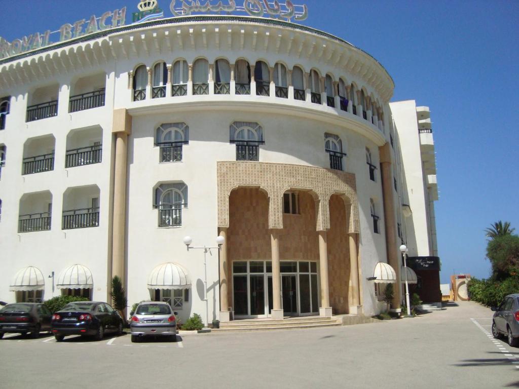 un gran edificio blanco con coches aparcados en un aparcamiento en Hotel Royal Beach, en Sousse