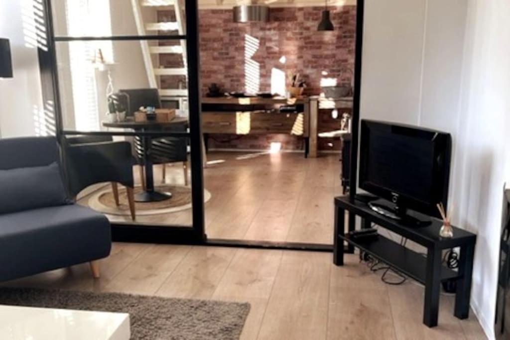 een woonkamer met een tv en een spiegel bij Gezellige knusse studio met bubbelbad in Huizen