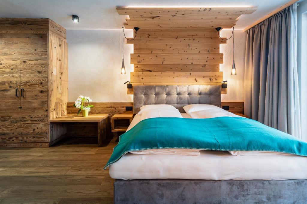 ein Schlafzimmer mit einem großen Bett und einer Holzwand in der Unterkunft Garni Mia Co in Antermoia