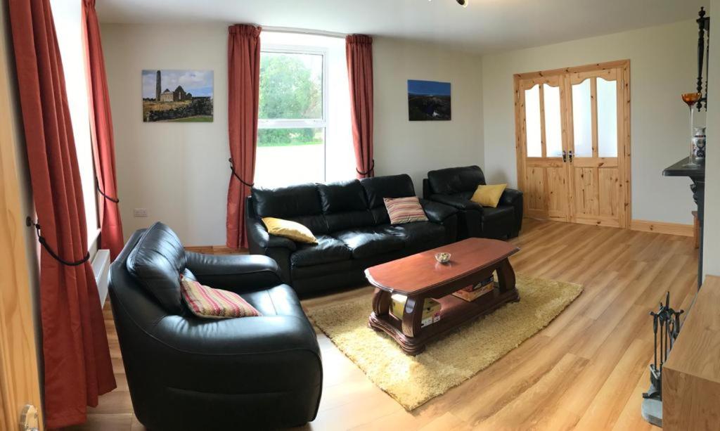 een woonkamer met een zwarte leren bank en een tafel bij Joes Cottage in Droíchead an Chláir