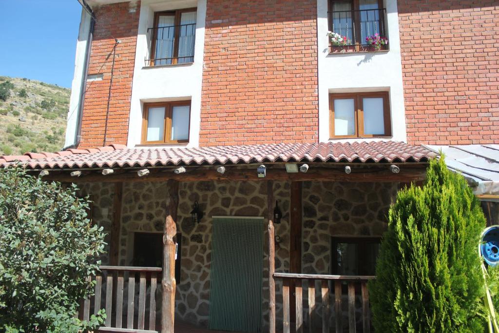 Las Tejeruelas Casa Rural في Navacepedilla de Corneja: منزل به باب أخضر ونوافذ