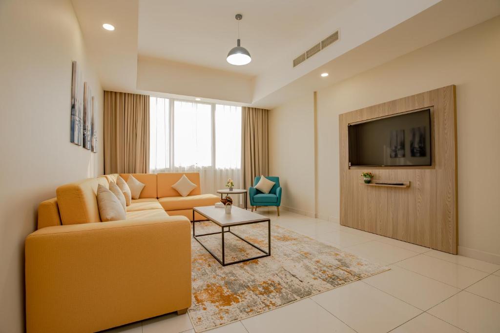 a living room with a couch and a tv at Platinum Coast Hotel Apartments in Fujairah