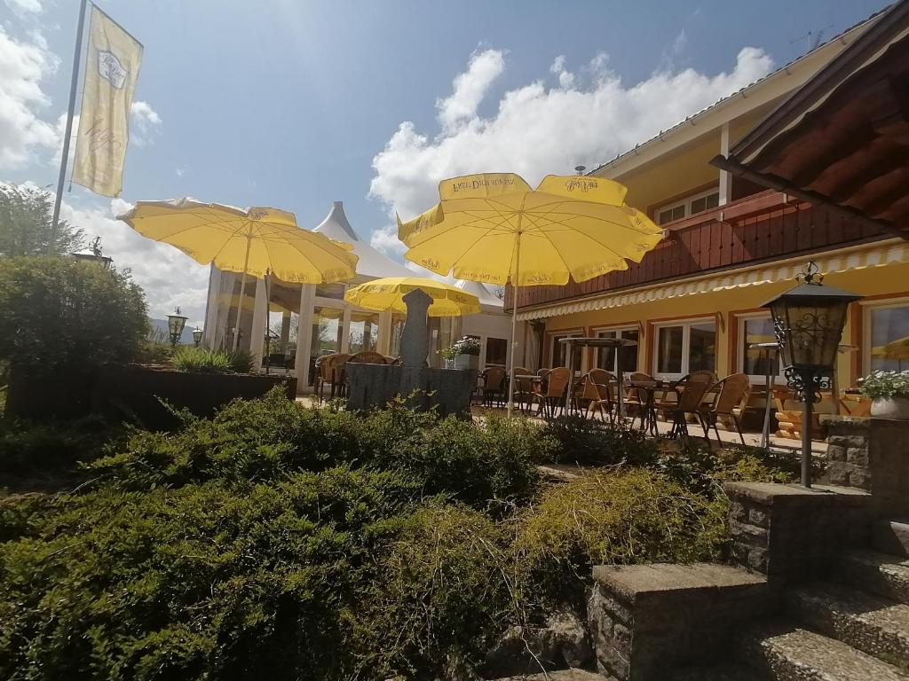 a restaurant with yellow umbrellas and tables and chairs at Helgas Landhotel in Oberreute