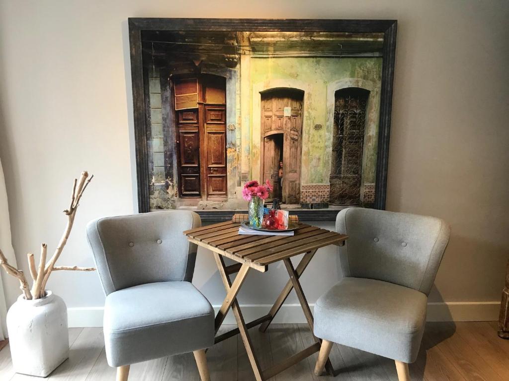 einen Tisch mit zwei Stühlen und ein Gemälde an der Wand in der Unterkunft Studio Pipper in Zandvoort