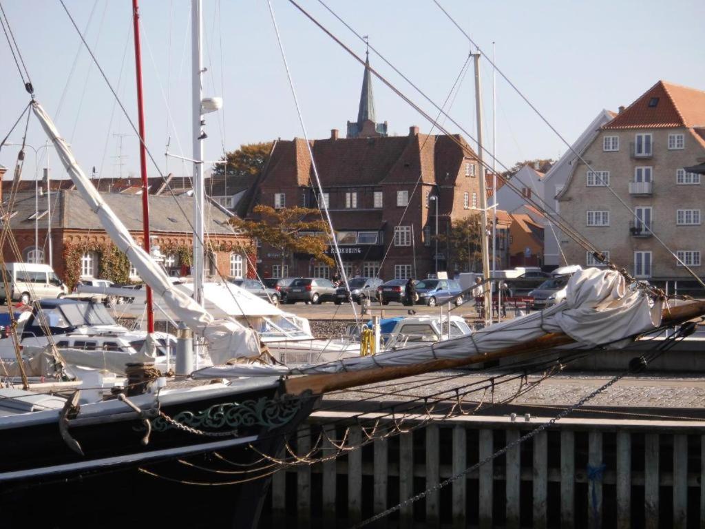 een zeilboot aangemeerd in een jachthaven met gebouwen bij Det Gamle Hotel Rudkøbing in Rudkøbing