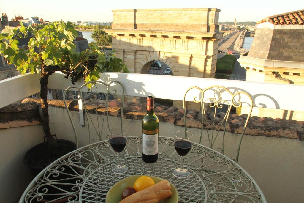 stół z dwoma kieliszkami wina i miską owoców w obiekcie Bordeaux Terrace w mieście Bordeaux