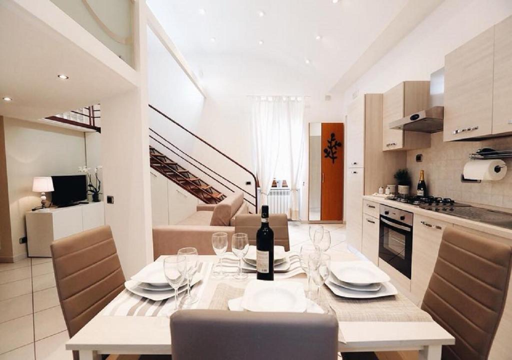 Maison Mele Luxury Apartment في نابولي: مطبخ وغرفة طعام مع طاولة مع كؤوس للنبيذ