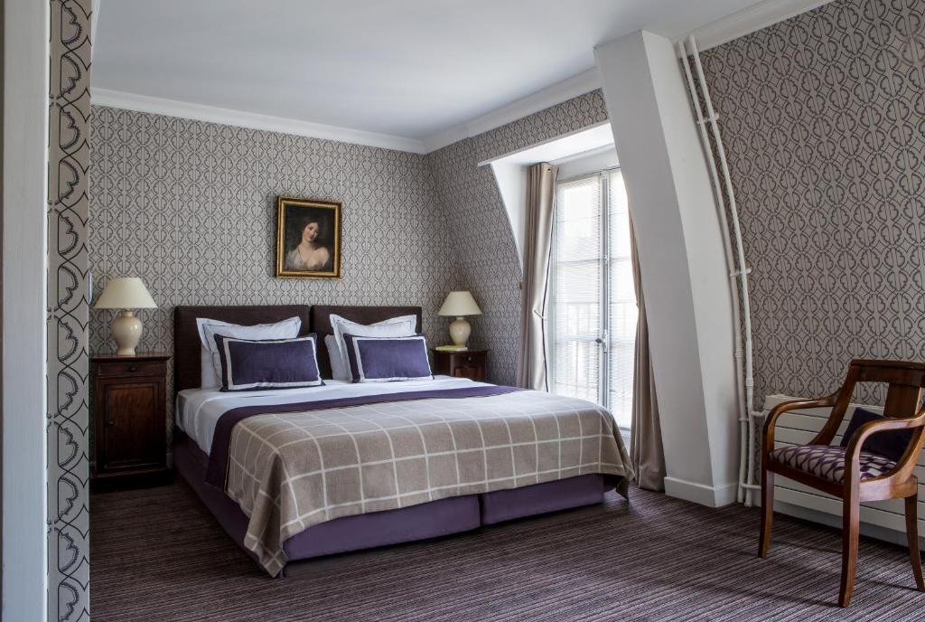 Un dormitorio con una cama con almohadas azules y una ventana en Hôtel d'Orsay - Esprit de France, en París