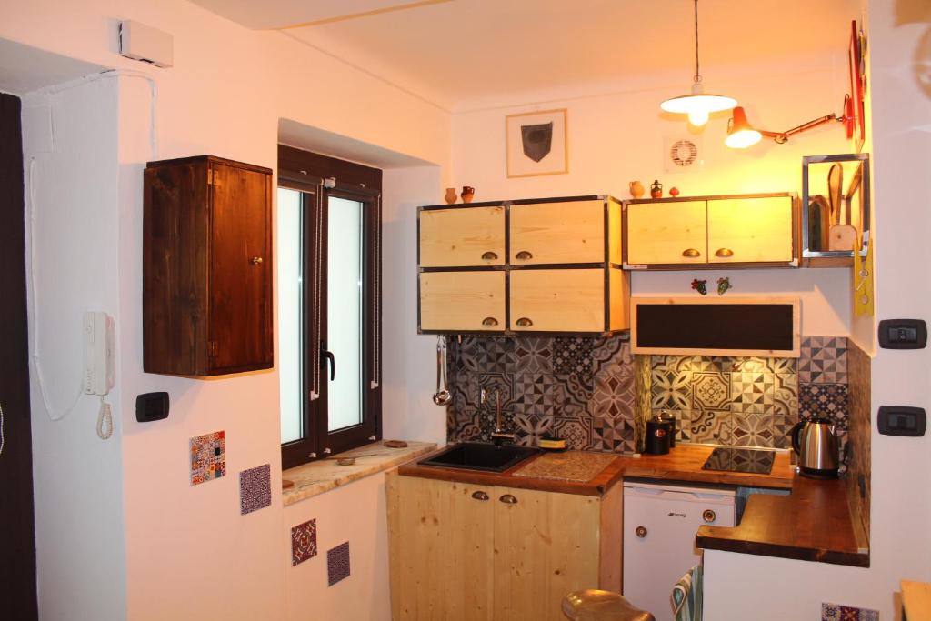 une cuisine avec des placards en bois et une fenêtre dans l'établissement L'ango-letto industriale del Quadrilatero Romano, à Turin