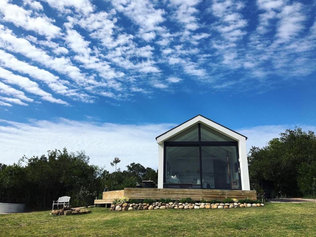 een gebouw met een groot raam op een veld bij Hillandale Hideaway in Plettenbergbaai