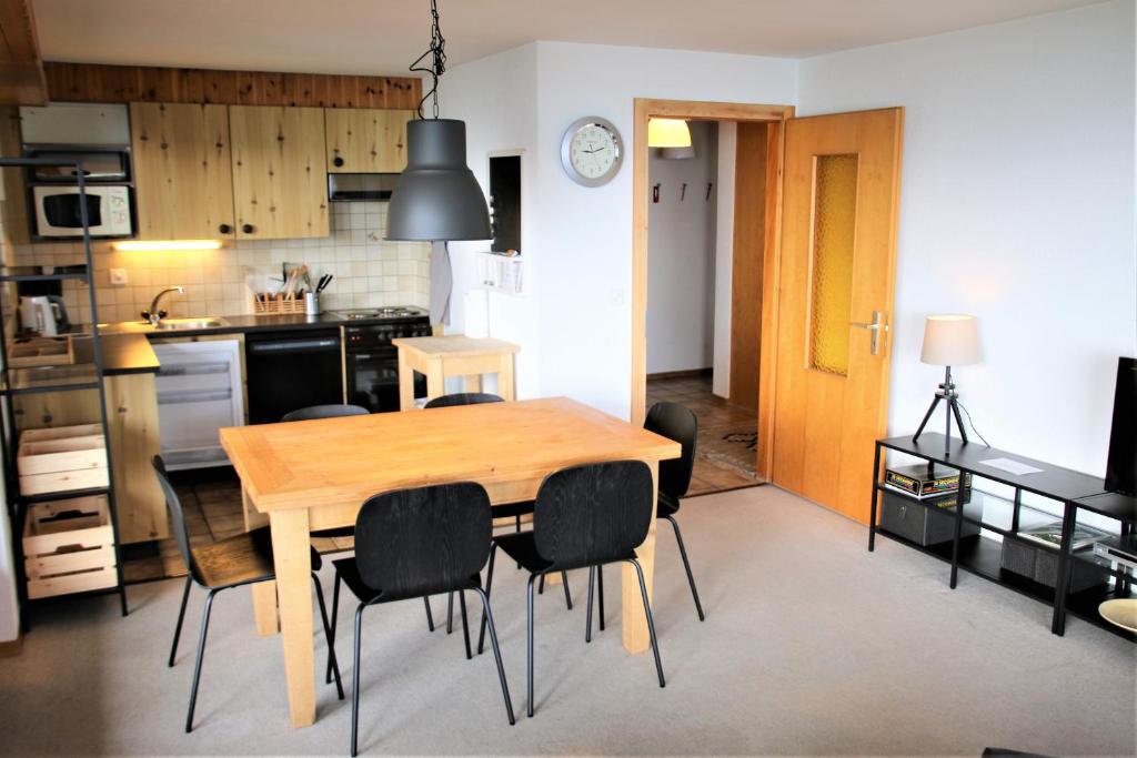 a kitchen and dining room with a wooden table and chairs at Orée du Bois PLEASANT & COSY apartments in Sion