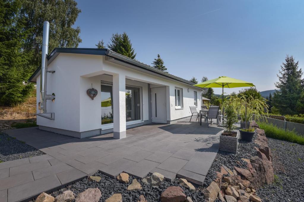 una casa bianca con patio e ombrellone di Ferienhaus am Fusse des Rennsteig/ Haus Anna a Suhl