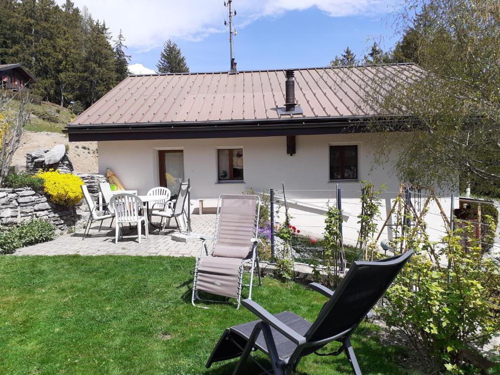 einen Garten mit Stühlen, einem Tisch und einem Haus in der Unterkunft Les loulou in Savièse