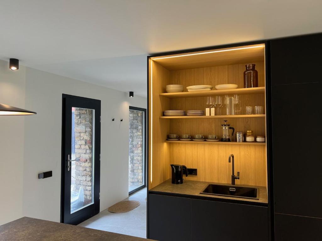 a kitchen with a sink and a shelf with dishes at Liepu māja in Liepāja