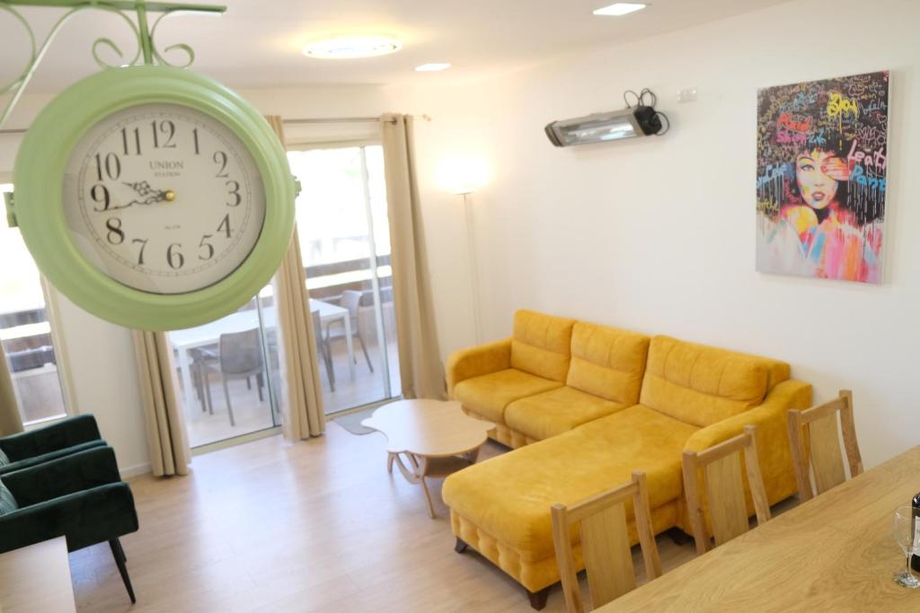 a living room with a couch and a clock on the wall at Hermon Suites in Majdal Shams