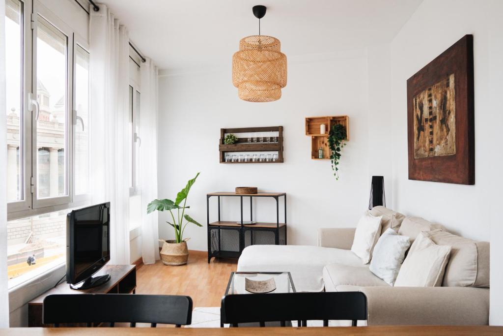 a white living room with a couch and a tv at Sunny and modern apartment ideal for groups in Barcelona