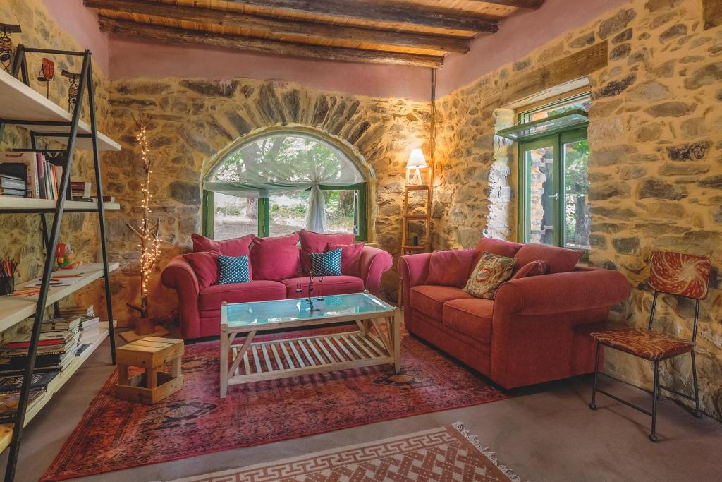una sala de estar con 2 sofás rojos y una pared de piedra. en Hani Kastania - Chania retreat for families and groups for holidays and workshops en Sémbronas