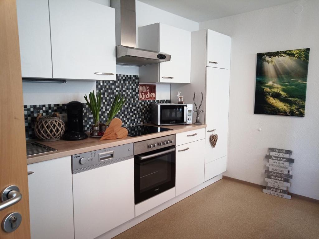 a kitchen with white cabinets and a stove top oven at Ferienwohnung Altmüüültal in Berching