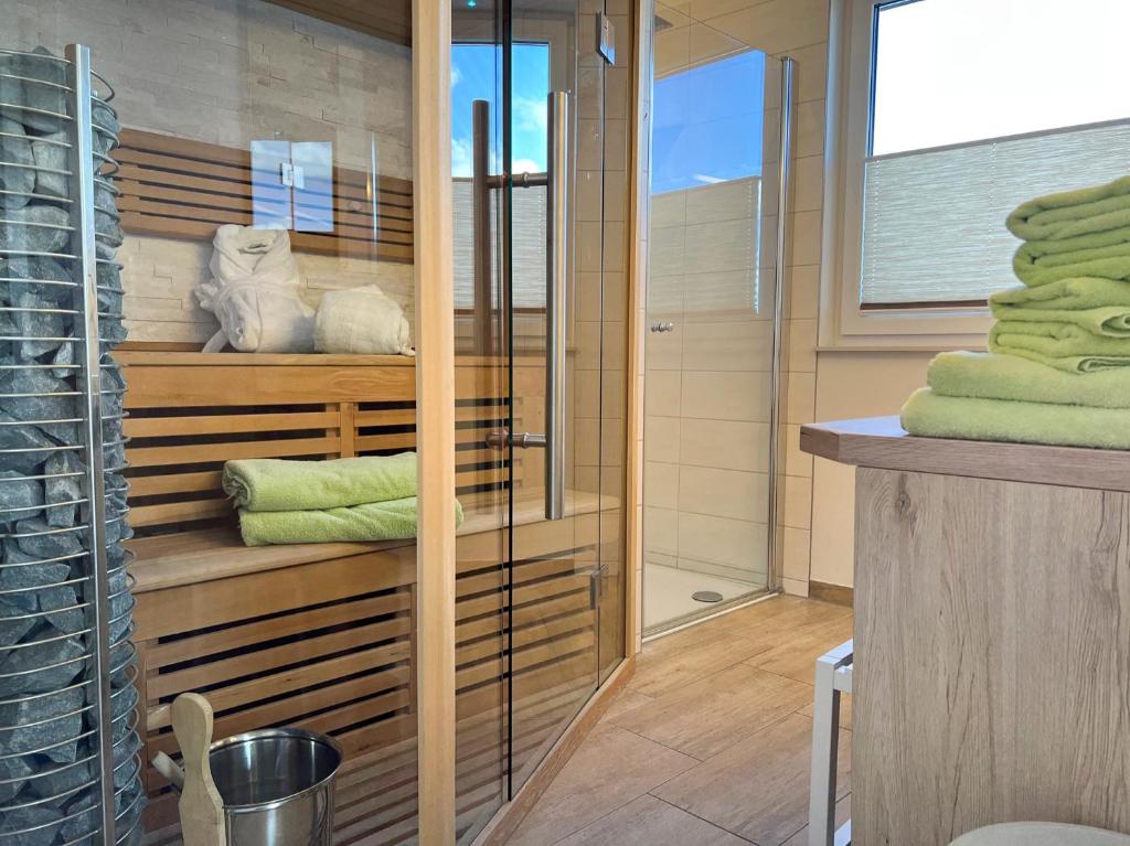 a bathroom with wooden shelves and green towels at ZUM LEUCHTTURM Wellness-Appartement APPARTO Grömitz in Grömitz