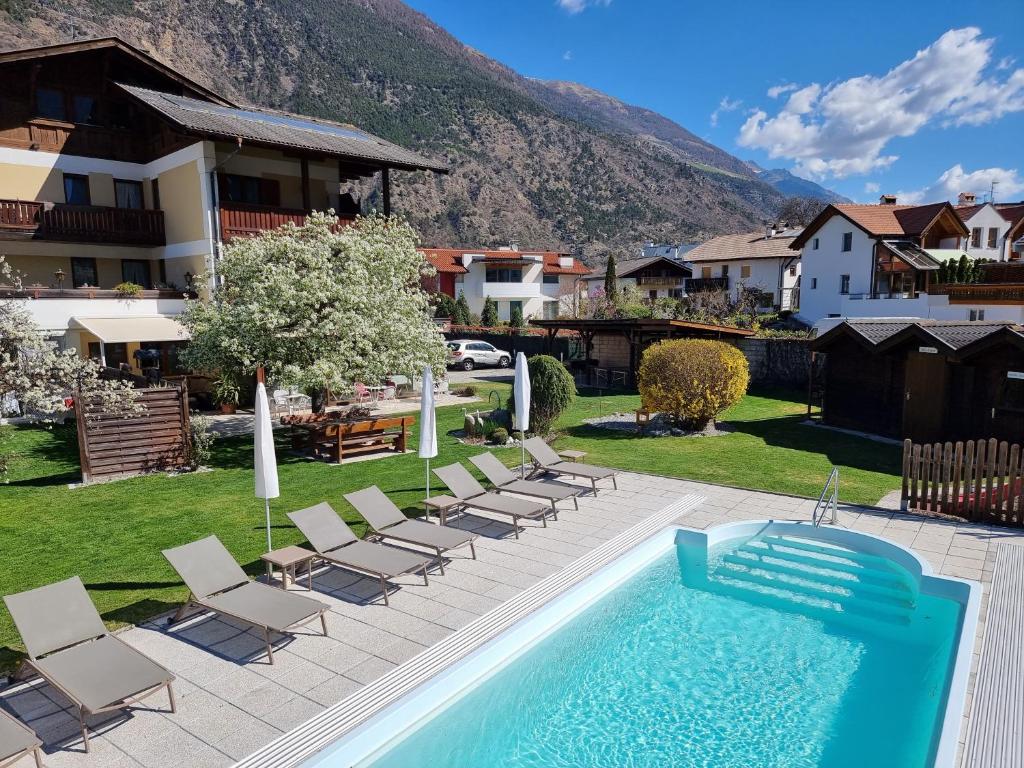 a swimming pool in a yard with chairs and a house at Pension Sattlerenglhof in Laces