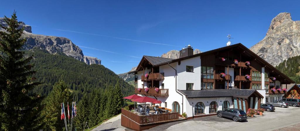 a hotel in the mountains with cars parked in front of it at Sporthotel Panorama in Corvara in Badia