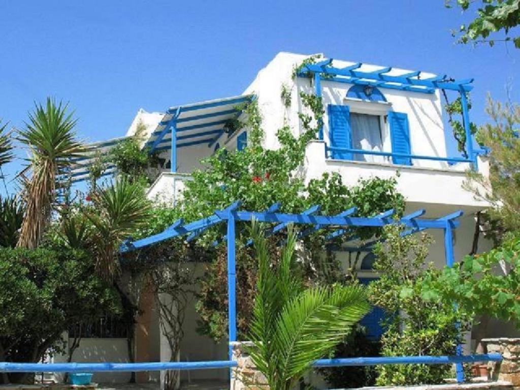 una casa blanca con persianas azules y plantas en ella en Sea View Studios & Apartments, en Agia Anna de Naxos