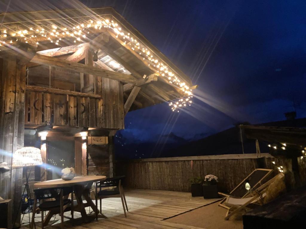 - une terrasse avec une table et des lumières la nuit dans l'établissement Charmant Mazot Le 1881 4 pers, à Demi-Quartier