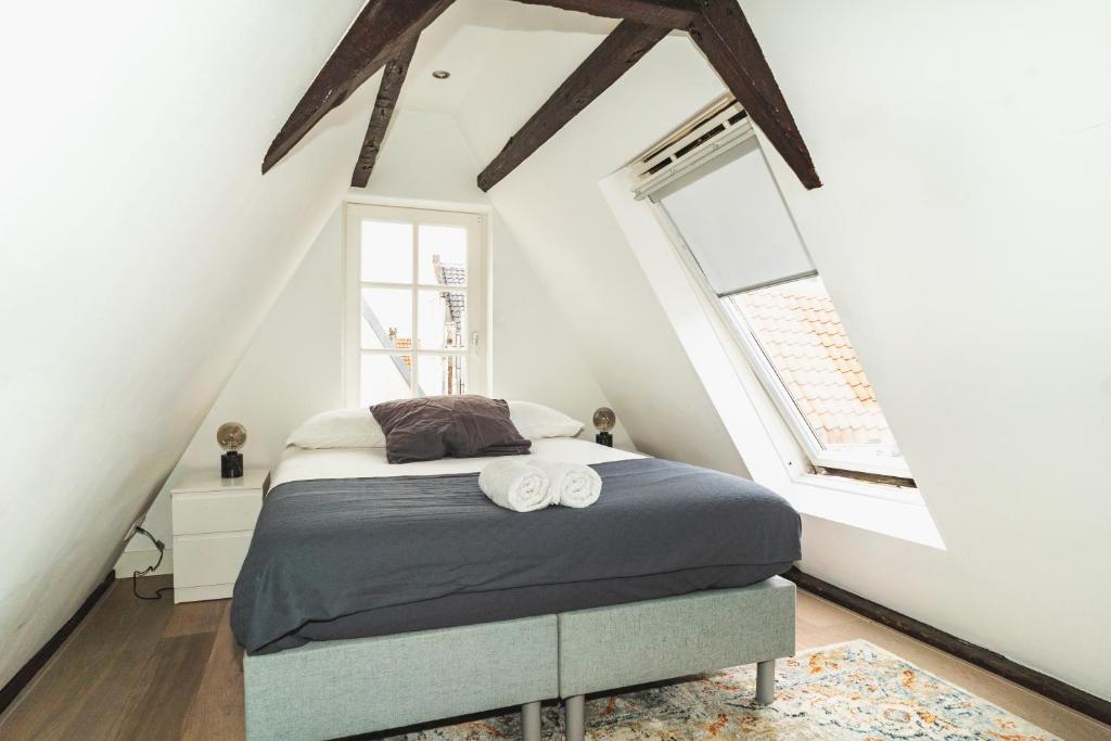 a bedroom with a bed and two windows at Tiny Attic on the Herengracht, Private Room in Amsterdam